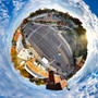 A 360-degree panoramic Spherescape of an intersection in Portland, Maine, featuring the "Hopeful" neon sign above a brick building, with a striking autumnal tree canopy and a clear blue sky reflected in a spherical distortion, creating an encapsulated view of the urban scene.