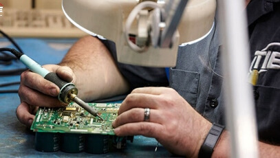 Close-up of TIE Industrial technician soldering Fanuc parts