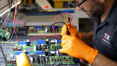 TIE Industrial employee wearing orange gloves and performing repair services