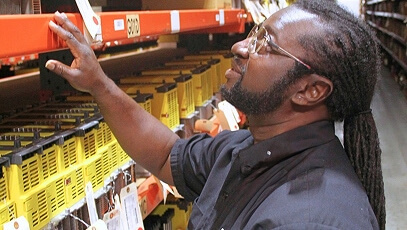 TIE Industrial technician looking through shelves of Fanuc parts in warehouse