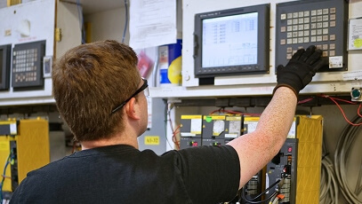 TIE Industrial technician testing repaired teach pendant with robot in warehouse