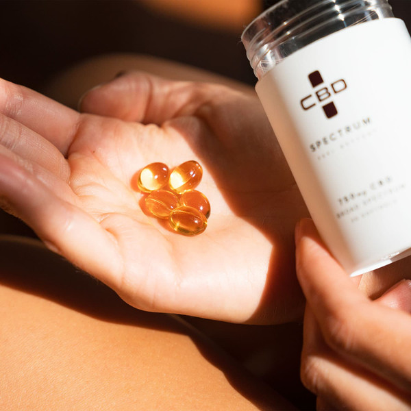 Open hand holding several Spectrum CBD softgels