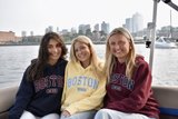 Boston 1630 appliqué hooded sweatshirt featuring collegiate-style lettering, available in maroon, navy, and butter yellow colors with a front kangaroo pocket and adjustable hood.