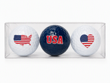 Three patriotic golf balls in a clear display box featuring red white and blue themed artwork and collectible gift packaging.