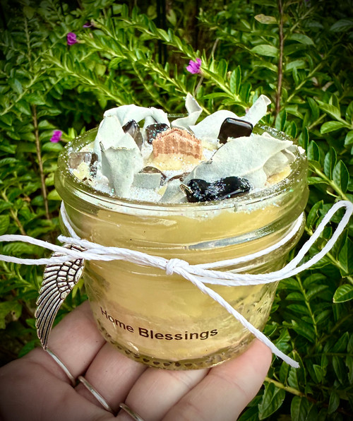Home Blessings Candle made with local beeswax and a wood wick. Scented with essential oils of rosemary, orange, cedar wood, and clove. Topped with white sage leaves and smoky quartz crystal chip stones. Healthy to burn with no paraffin or artificial fragrances.