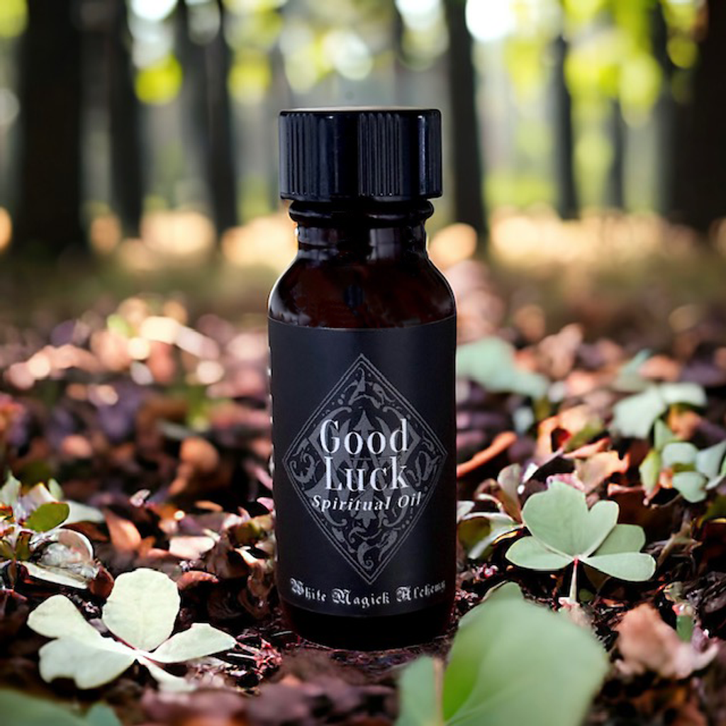 An amber bottle in a forest with four leaf clovers with a black label that reads Good Luck Spell Oil by White Magick Alchemy
