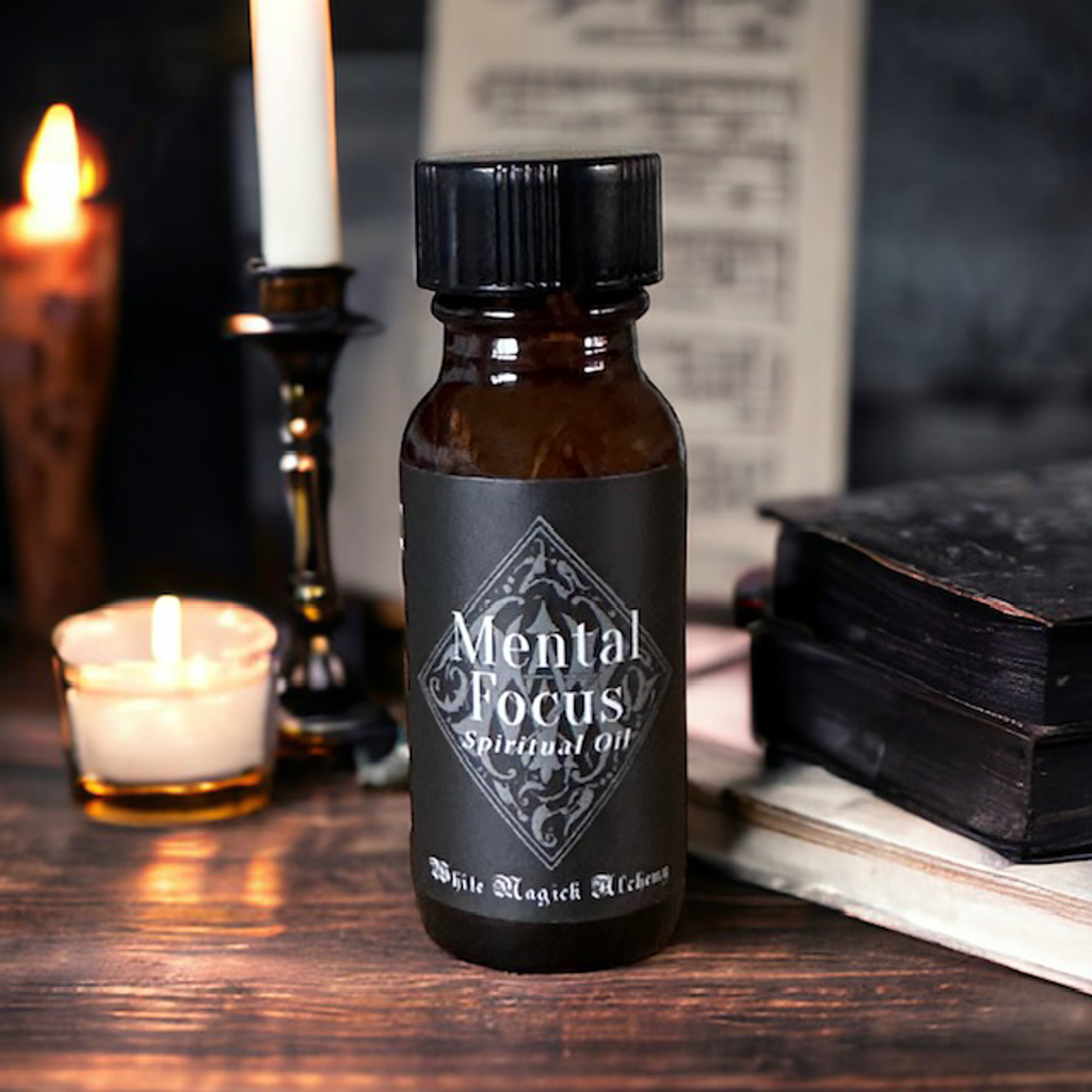 An amber bottle on a wood table with candles in the background with a black label that reads Mental Focus Spell Oil by White Magick Alchemy