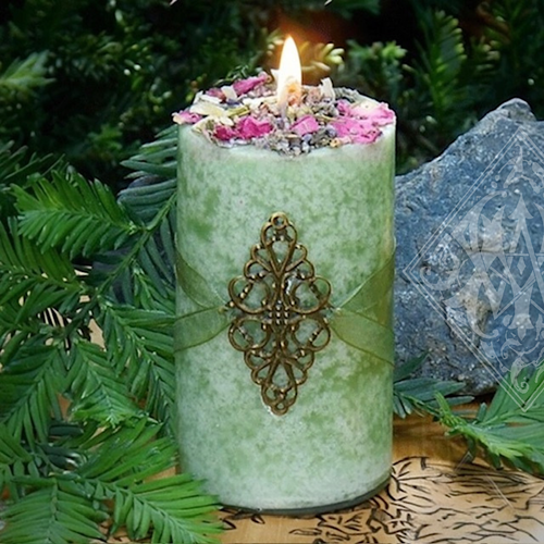 green goddess candle sitting in forest with rocks