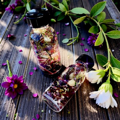 ostara ritual spell oil with flowers and crystals in a clear bottle in the garden