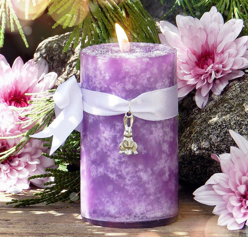 orchid candle with bunny rabbit charm tied around it in a spring ostara garden
