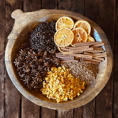 witches brew herbs and spices in a big wooden bowl, cloves, orange, cinnamon, anise