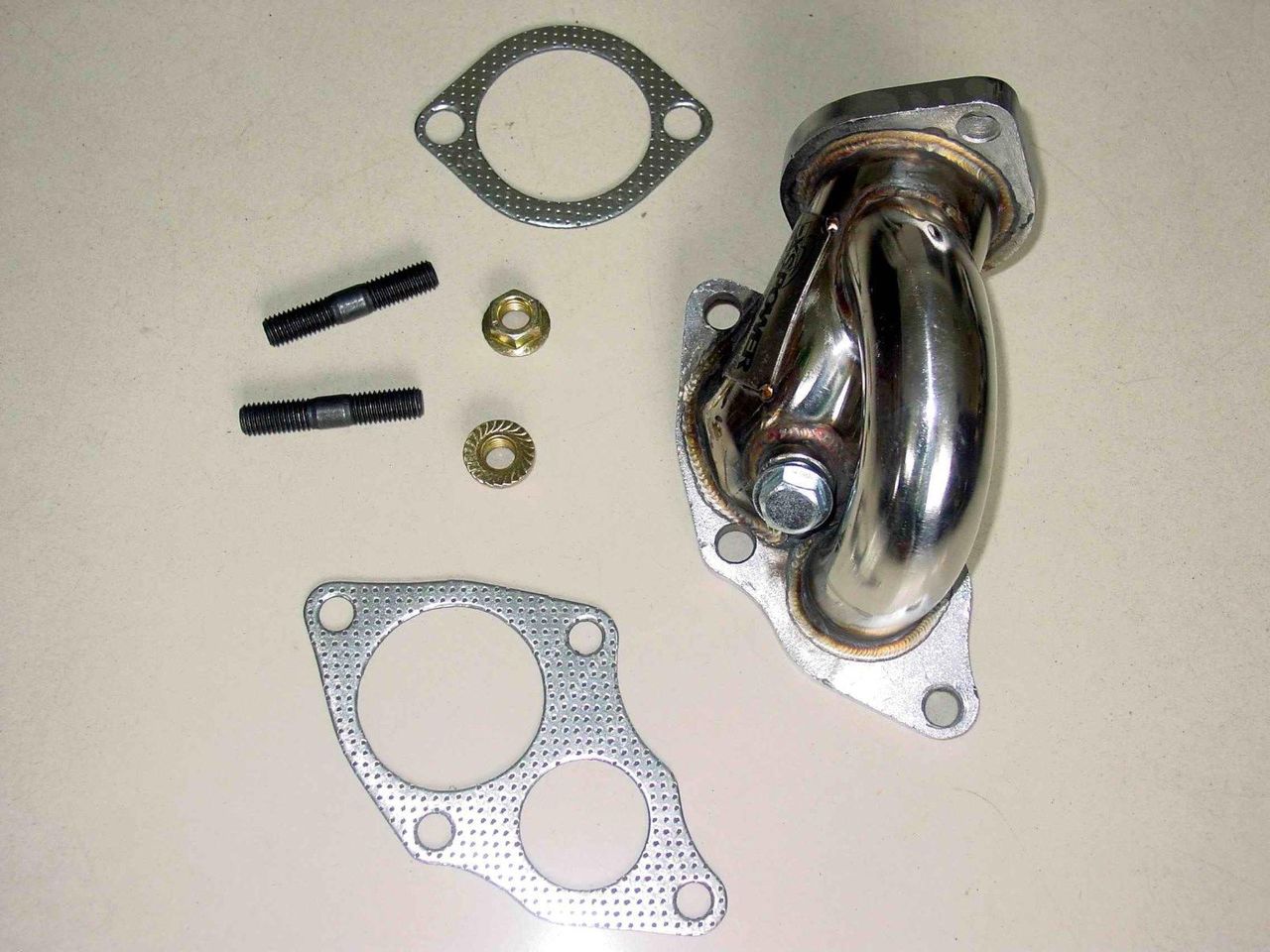 High-flow stainless steel turbo outlet dump pipe designed for DSM 4G63T applications using TD05 16G, 18G, and 20G turbochargers. Features mandrel-bent tubing, CNC-machined flanges, TIG and MIG welded construction, mirror-polished finish, and integrated O2 sensor bung. Direct bolt-on fitment for Mitsubishi Eclipse GST/GSX, Eagle Talon TSi, Plymouth Laser RS Turbo, and Galant VR-4 models.