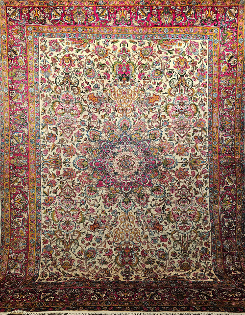 Vintage Persian Kerman Lavar room size rug. Hand-woven. All-over colorful floral design. Ivory background. Design colors: crimson, pink, green, blue, and others. Single crimson border. Full pile. Wonderful condition.