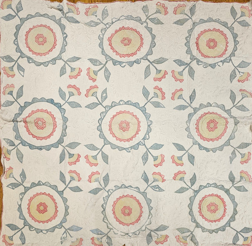 19th century Pennsylvania Dutch hand-stitched appliqué quilt with flower and circle motifs in pale green, yellow, and red on an ivory background, displayed as antique textile wall art, The Persian Knot Gallery, SKU: 2355