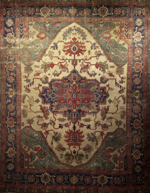 Late 19th-century Turkish Heriz Serapi rug with pale yellow field, green medallion, and dark blue border.