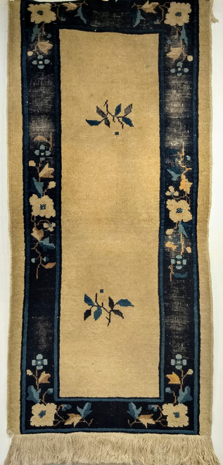 Late 19th century Chinese Peking rug with tan field, two floral bouquets, and navy border with leaf patterns.