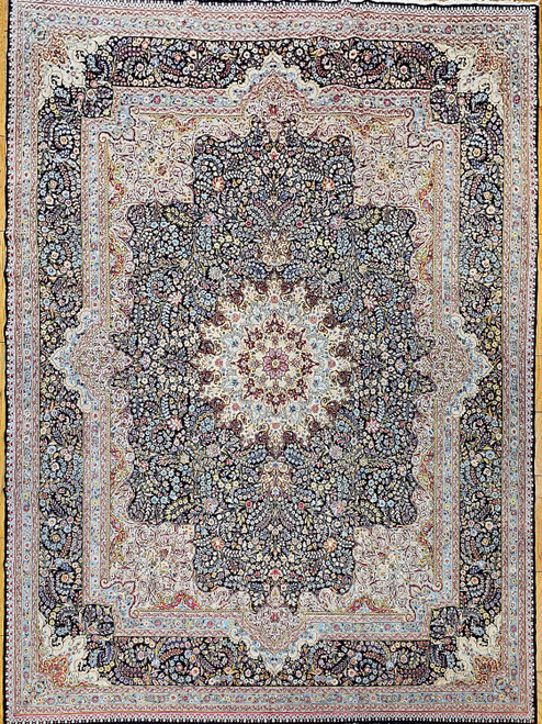 Early 20th Century Vintage Persian Kerman Lavar area rug. Handwoven. Millefleur (a thousand flowers) floral design. "Persian Gardens" pattern. Dark blue field. Corners in ivory, pink, pale blue, green, and red. Cream central medallion with flowers. Dark blue primary border with flower design.