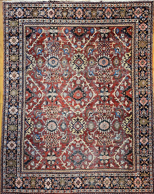 Late 19th Century Antique Persian Mahal Sultanabad area rug. Hand-woven. All-over geometric pattern. Brick-red color field. Border with geometric forms in a dark blue background. Colors: red, blue, pink, green, brown, and yellow.