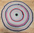 A vibrant and beautifully preserved antique American braided round rug dating to the second quarter of the 20th century, circa 1940s. This handcrafted folk art textile showcases a radiant color palette of red, white, blue, green, yellow, and gray—woven to