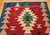 Vintage Turkish Kilim area rug with geometric medallion pattern in red, ivory, green, and navy, hand-woven mid-century textile.