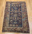 19th century Caucasian Shirvan area rug with navy blue field, ivory geometric border, and rust, green, and yellow accents, hand knotted with natural dyes, The Persian Knot Gallery, SKU: 2312