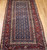 Late 19th Century Antique Kurdish gallery-size rug. Hand-woven. Paisley pattern. Blue background. Predominantly rust-colored border. Ideal for a hallway or as a wide runner.