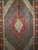 Early 20th century Persian Tabriz Mahi rug with geometric diamond medallions in cream, red, blue, and green. A fine hand-knotted collectible for luxury interiors.
