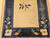 Late 19th century Chinese Peking rug with tan field, two floral bouquets, and navy border with leaf patterns.
