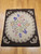 Vintage American hand-hooked floral rug from the early 1900s in brown, ivory, purple, pink, and blue with a wide brown border in a near-square format, The Persian Knot Gallery, SKU: 1443