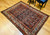 Early 20th Century Vintage Persian Malayer area rug. Hand-knotted. All-over paisley "seed of life" pattern. Navy blue field. Paisley forms in green, blue, yellow, pink. White border with flower designs in red, yellow, green, pink. Artisan village weaving.