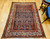 Early 20th Century Vintage Persian Malayer area rug. Hand-knotted. All-over paisley "seed of life" pattern. Navy blue field. Paisley forms in green, blue, yellow, pink. White border with flower designs in red, yellow, green, pink. Artisan village weaving.
