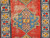Handwoven early 20th century Kazak rug featuring bold royal blue and yellow medallions on rich red background, The Persian Knot Gallery, SKU 1787
