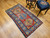 Handwoven early 20th century Kazak rug featuring bold royal blue and yellow medallions on rich red background, The Persian Knot Gallery, SKU 1787