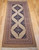 Mid-20th Century Vintage Persian Malayer gallery or corridor size rug. Handwoven. Open-field design on camel hair background. Three axial medallions in deep navy with geometric motifs in baby blue, pink, French blue. Cream field with paisley motif. Corner