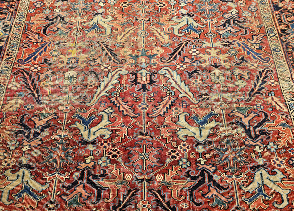 Antique Persian Heriz Serapi rug with near-square shape in terracotta, green, blue, and yellow, featuring botanical motifs and all-over design – early 1900s.
