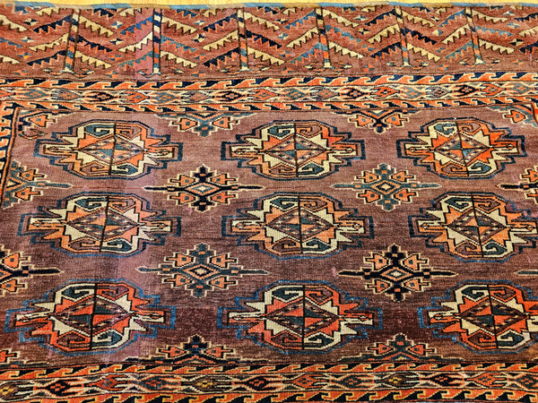 Antique Yomut Chuval bag with 3×3 Turkmen Gul medallion design in red, green, brown, and blue, and kilim back with multicolor stripes. Early 1900s textile.
