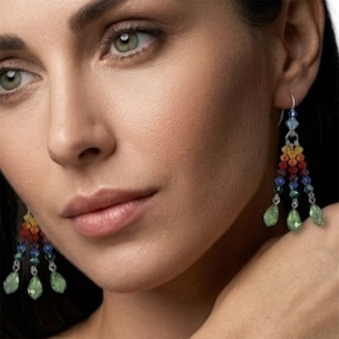 Model wearing  rainbow 3 strand earrings designed especially for pride month.  rainbow dangle earrings are sterling silver with swarovski crystals and include vintage peridot drop pear shapes. limited edition by designer karen curtis