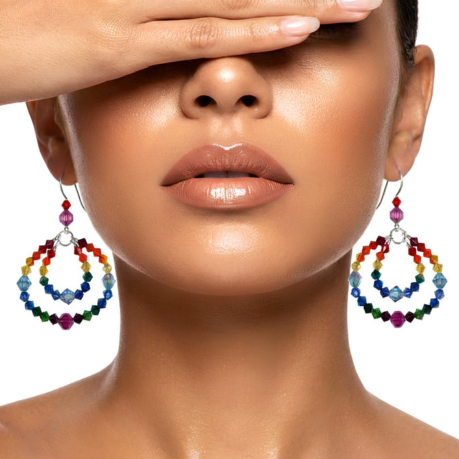 designer wearing double hoop rainbow earrings for pride month.  rainbow hoop earrings are sterling silver with swarovski crystals by designer karen curtis. paired with matching bangle bracelet