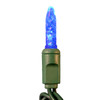 Blue M5 faceted LED Christmas light bulb illuminated and mounted in a green socket. The bulb has a narrow, textured surface that enhances its glow, and is connected to a twisted dark green wire.