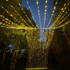A stunning 10' x 30' warm white LED light curtain is gracefully displayed, with 3,600 tiny glowing lights cascading down in evenly spaced rows. The warm white light creates a soft, inviting ambiance, ideal for festive events or cozy décor. The expansive size provides a dramatic effect, covering a large walls, windows, or outdoor spaces. The gentle glow of the LEDs beautifully illuminates the surroundings, offering a magical, twinkling backdrop perfect for any occasion.