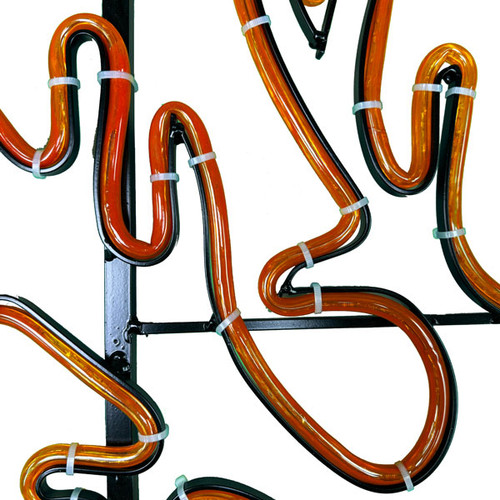This close-up image shows orange LED rope light tubing secured to a black metal frame using white zip ties. The tubing is shaped into smooth curves, illustrating how the lights are precisely fastened to create detailed outlines for decorative displays. This close-up image shows orange LED rope light tubing secured to a black metal frame using white zip ties. The tubing is shaped into smooth curves, illustrating how the lights are precisely fastened to create detailed outlines for decorative displays.