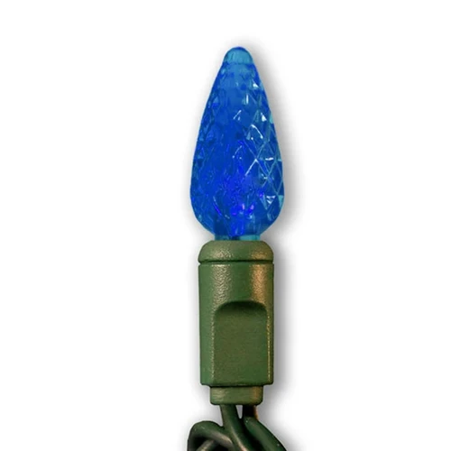 Blue C6 faceted LED Christmas light bulb mounted on a green plastic socket with a dark green wire. The bulb has a textured, diamond-cut surface that enhances its glowing effect when illuminated.