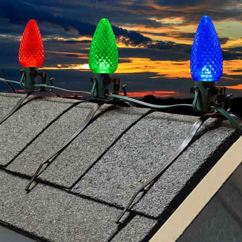 Durable plastic C7/C9 roof ridge line mounting clips securely fastened along a shingled roof, designed to hold traditional holiday light bulbs upright along roof peaks. These clips provide a clean, professional look with easy installation and strong grip—ideal for creating festive, symmetrical lighting displays without damaging shingles. Durable plastic C7/C9 roof ridge line mounting clips securely fastened along a shingled roof, designed to hold traditional holiday light bulbs upright along roof peaks. These clips provide a clean, professional look with easy installation and strong grip—ideal for creating festive, symmetrical lighting displays without damaging shingles.
