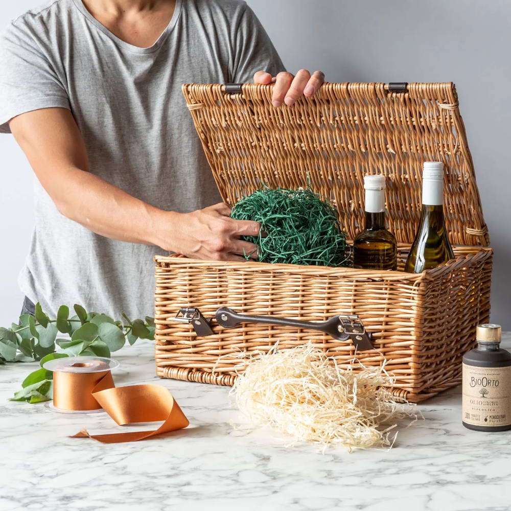 A hand putting shredded paper into an open wicker basket