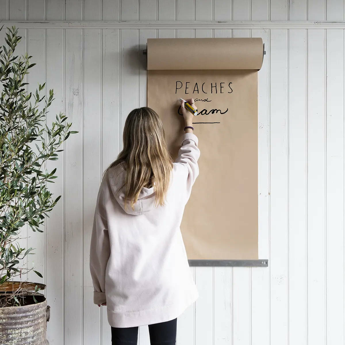 A person writing on a piece of paper attached to a wall