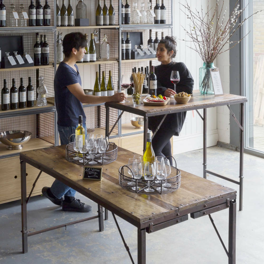 Two people standing at a high table with wine and nibbles