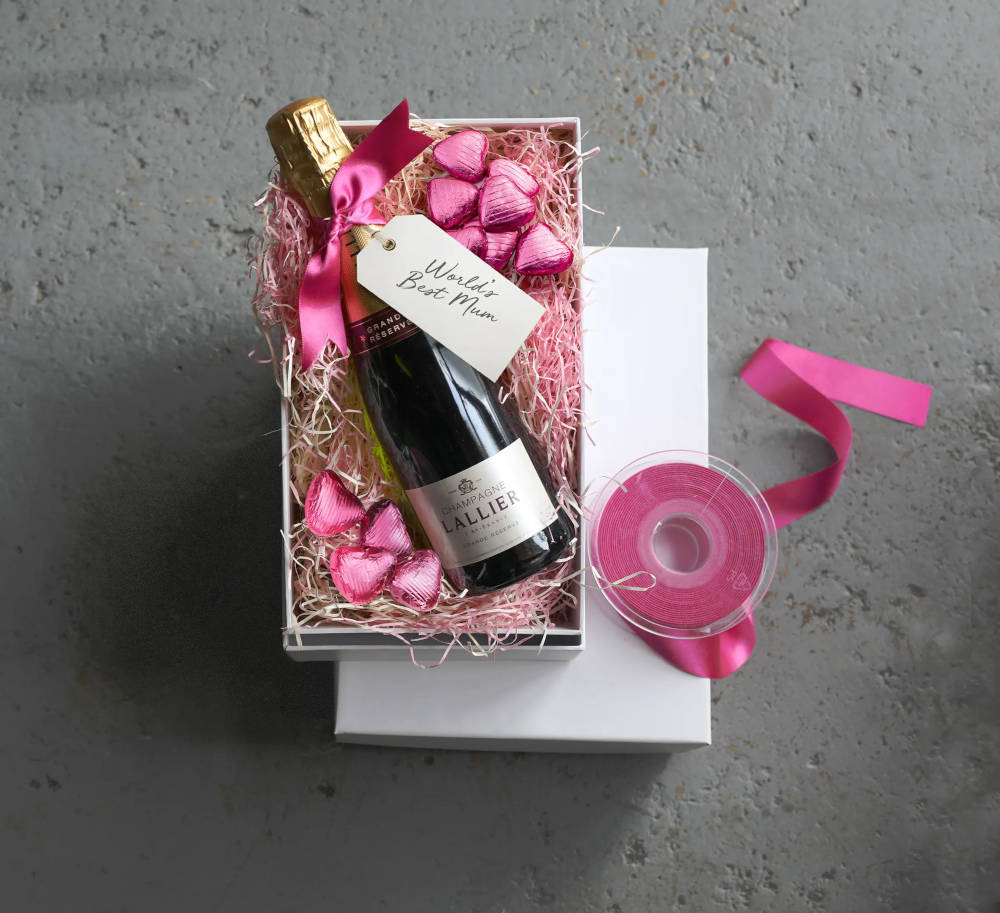 A white box with pink ribbon next to it, a bottle with heart shaped sweets inside