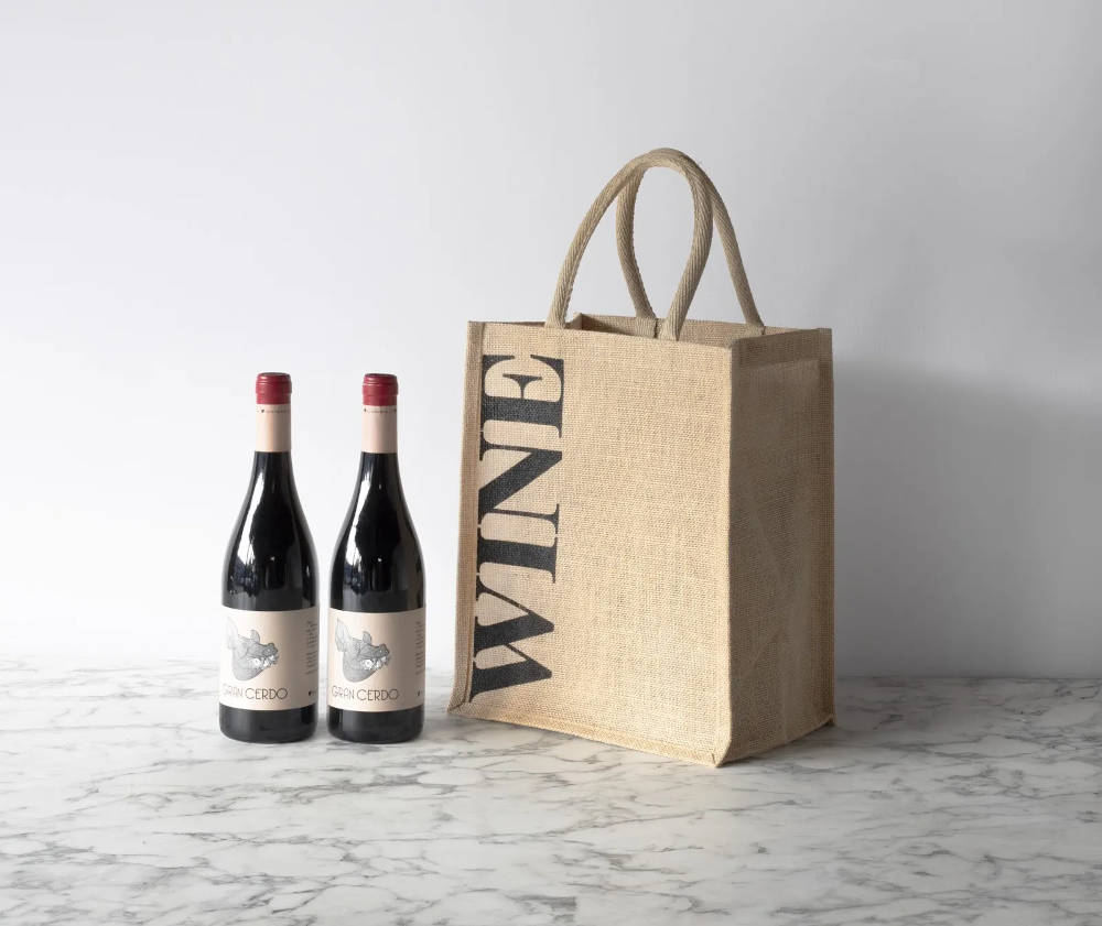 Two bottles of wine next to a jute bag with wine written on the side