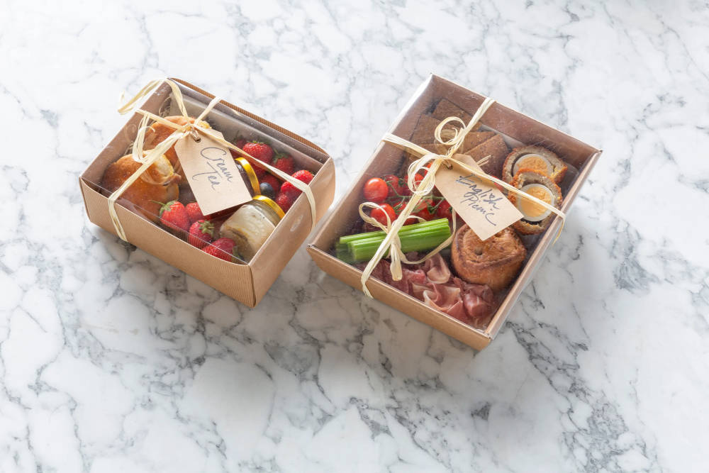 Two boxes neatly wrapped with bows, filled with various types of food