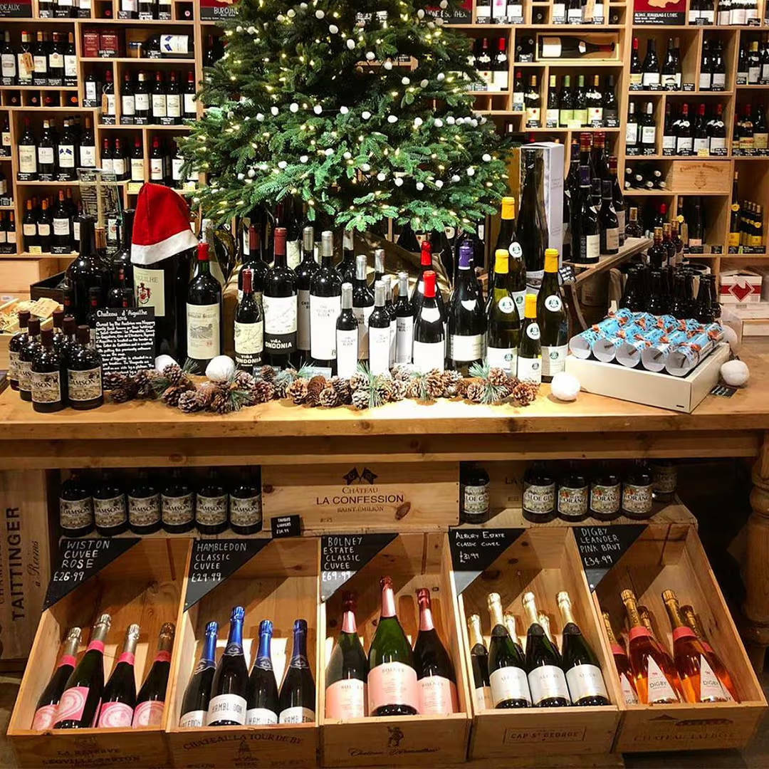 A table display with five boxes of wine below, on top a tree surrounded by bottles